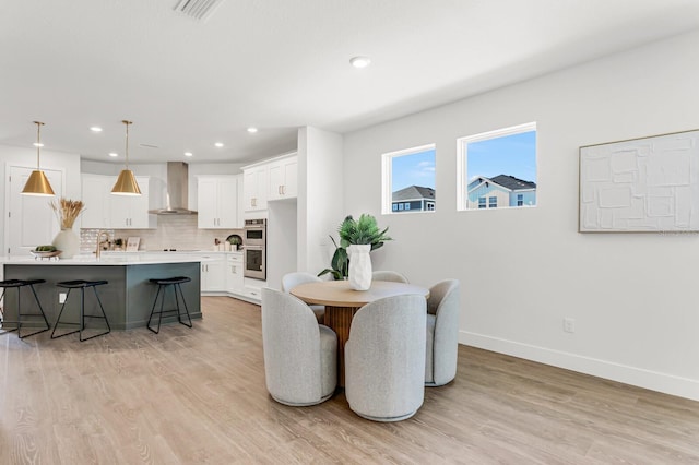dining area with baseboards, light wood-type flooring, and recessed lighting