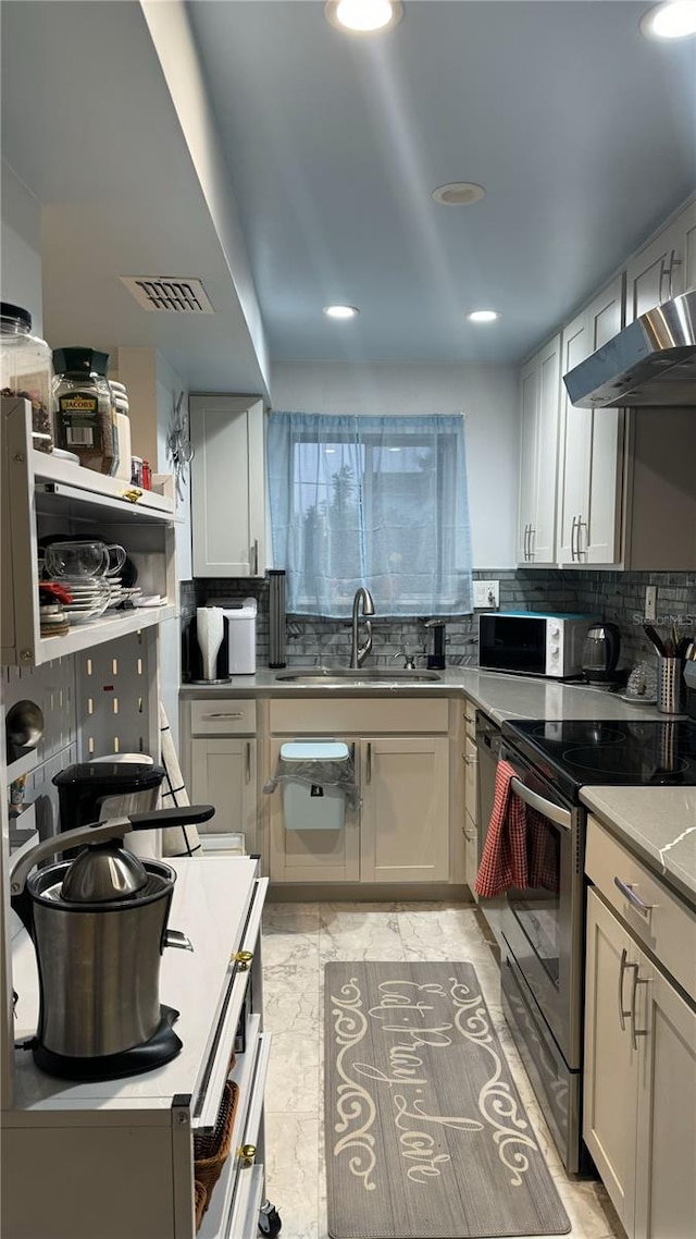 kitchen with decorative backsplash, stainless steel electric range oven, sink, and white cabinets