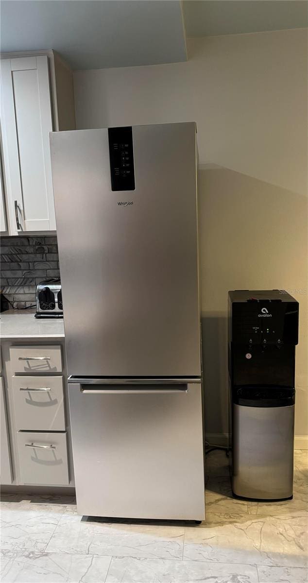 kitchen with white cabinets, stainless steel refrigerator, and backsplash