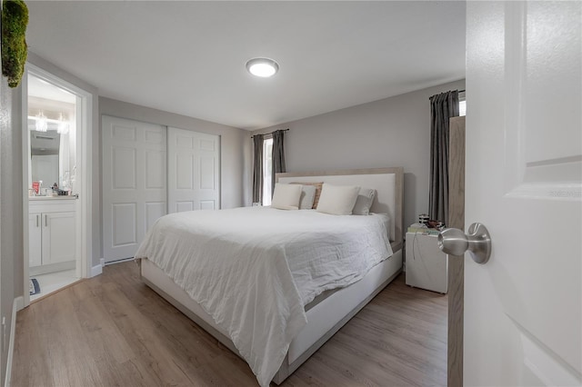 bedroom featuring light hardwood / wood-style flooring, a closet, and ensuite bath