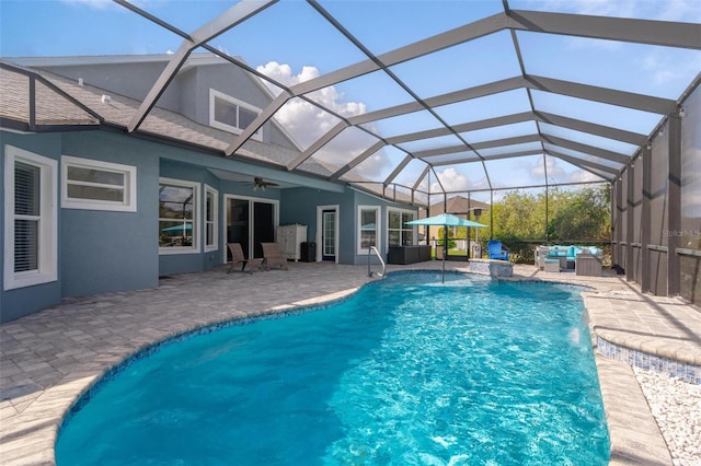 view of pool with outdoor lounge area, glass enclosure, ceiling fan, and a patio area