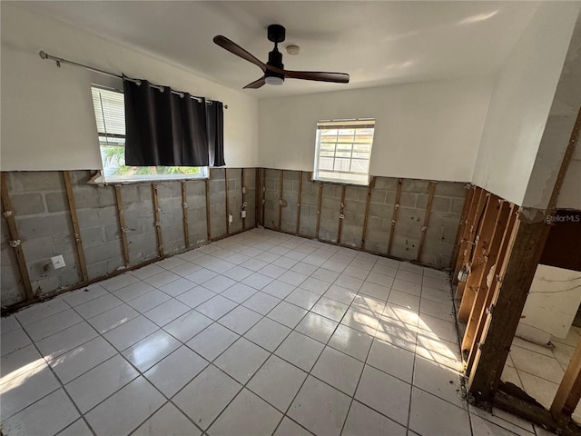 empty room featuring tile walls, ceiling fan, and light tile patterned floors