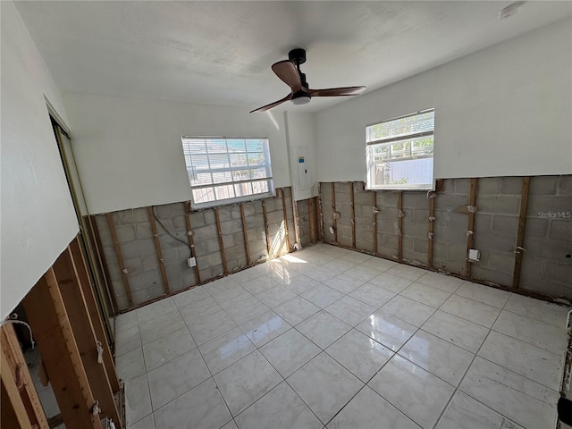 interior space with ceiling fan, tile walls, and a healthy amount of sunlight