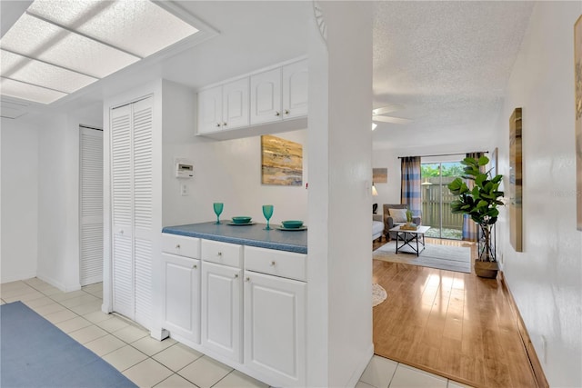 kitchen with white cabinetry, ceiling fan, light hardwood / wood-style floors, and a textured ceiling