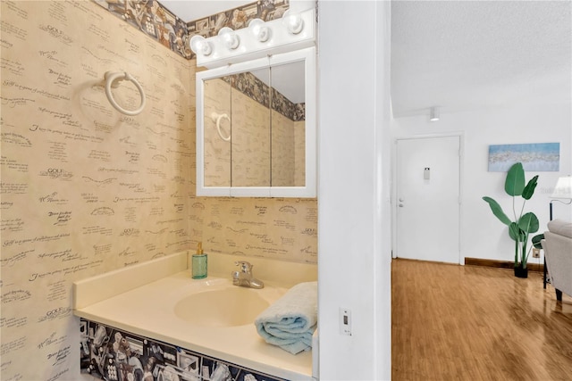 bathroom with hardwood / wood-style floors, vanity, and a textured ceiling