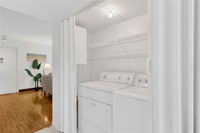 laundry area featuring washer and dryer, a textured ceiling, and light wood-type flooring