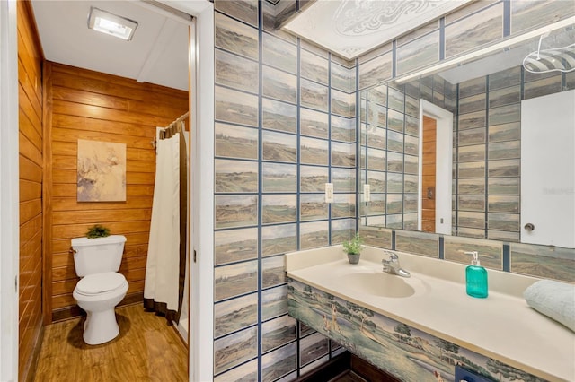 bathroom featuring walk in shower, sink, hardwood / wood-style flooring, toilet, and wood walls