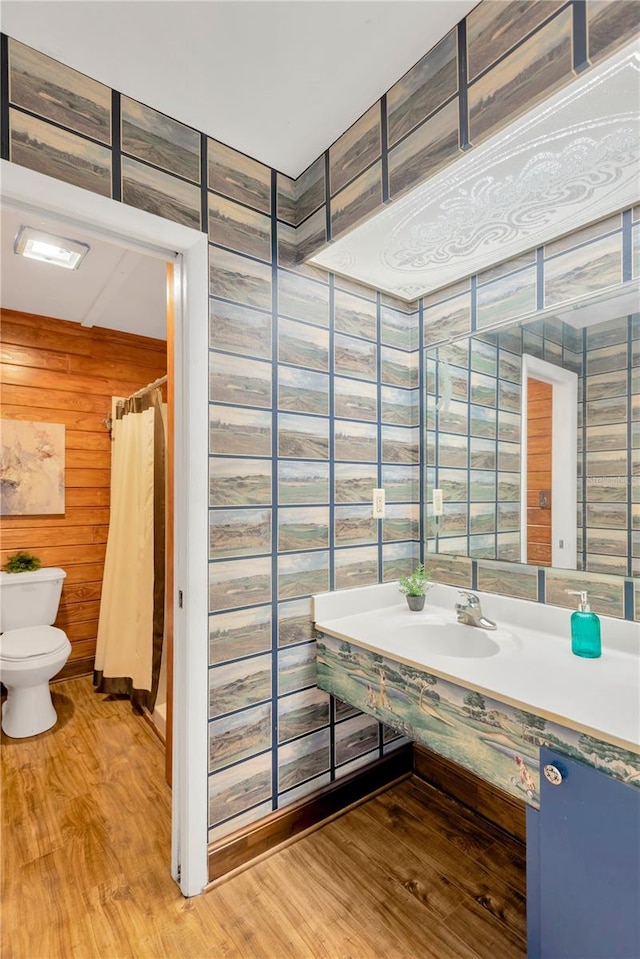 bathroom featuring curtained shower, wood walls, sink, and wood-type flooring