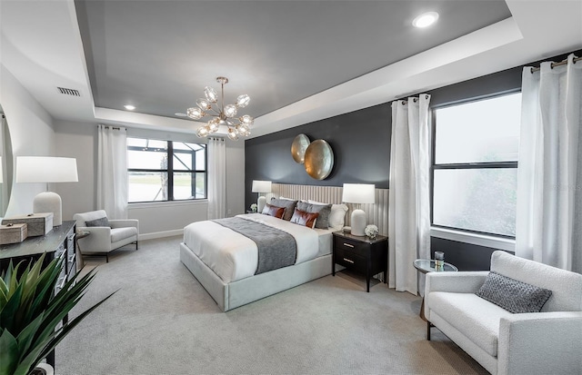 carpeted bedroom with an inviting chandelier and a raised ceiling