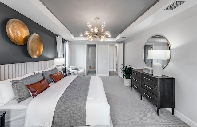 carpeted bedroom featuring an inviting chandelier and a tray ceiling