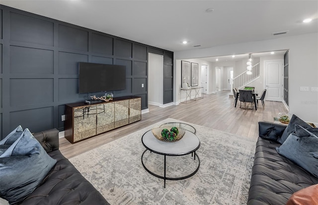 living room featuring light wood-type flooring and a notable chandelier