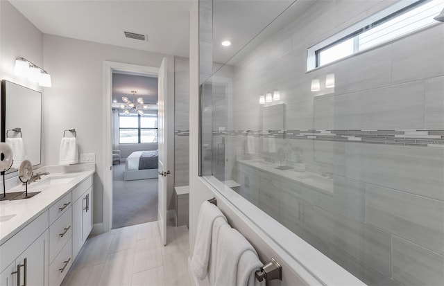 bathroom featuring tile patterned floors, vanity, a notable chandelier, and tiled shower