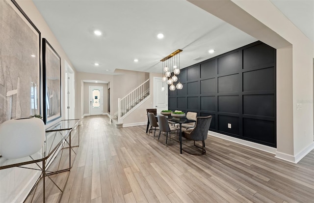 dining space featuring light wood-type flooring and an inviting chandelier