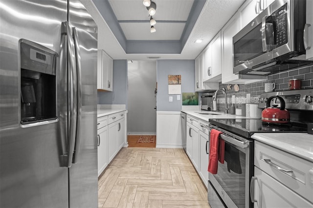 kitchen with backsplash, appliances with stainless steel finishes, sink, and white cabinets