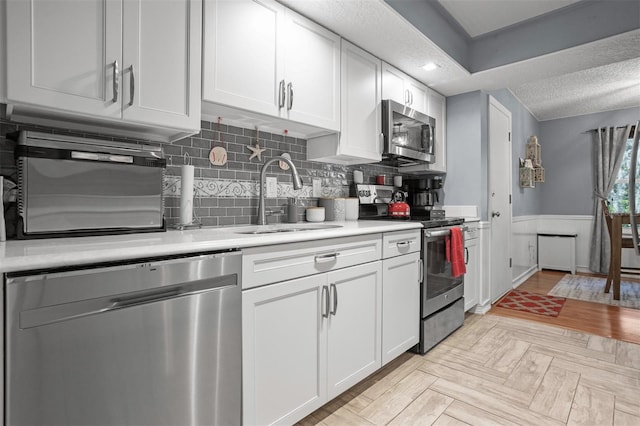 kitchen featuring white cabinetry, sink, decorative backsplash, and appliances with stainless steel finishes