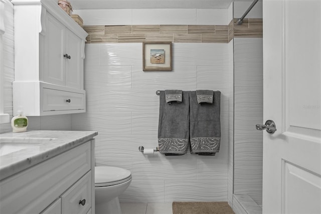 bathroom featuring tile patterned flooring, vanity, toilet, and tile walls