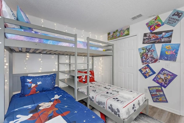 bedroom with a textured ceiling, hardwood / wood-style flooring, and a closet