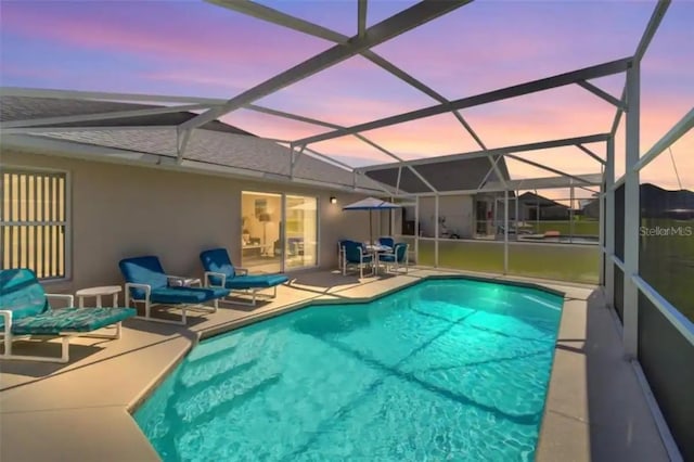 pool at dusk featuring a lanai and a patio area