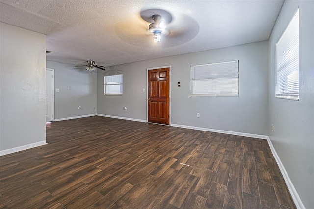 empty room featuring a textured ceiling, ceiling fan, a healthy amount of sunlight, and dark hardwood / wood-style floors