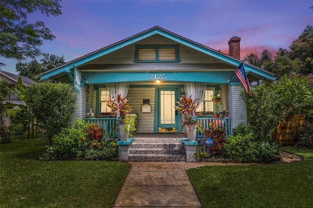 bungalow-style house with a yard and covered porch