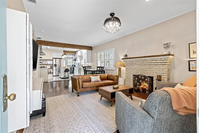 living room with a fireplace, light wood-type flooring, an inviting chandelier, and crown molding