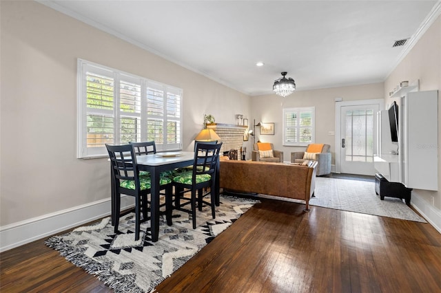 dining area with hardwood / wood-style floors, ornamental molding, and an inviting chandelier