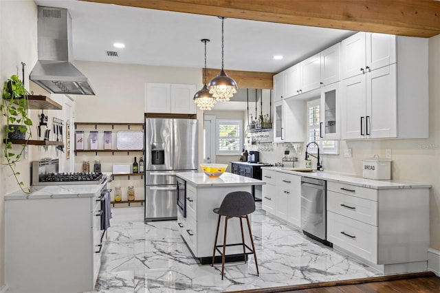 kitchen featuring white cabinets, a kitchen island, wall chimney range hood, and appliances with stainless steel finishes