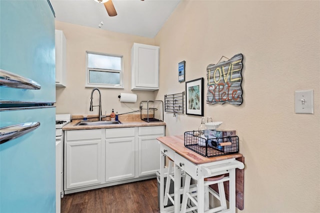 kitchen with stainless steel refrigerator, ceiling fan, sink, dark wood-type flooring, and white cabinets