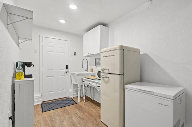 kitchen with white cabinets, white appliances, light hardwood / wood-style flooring, and sink