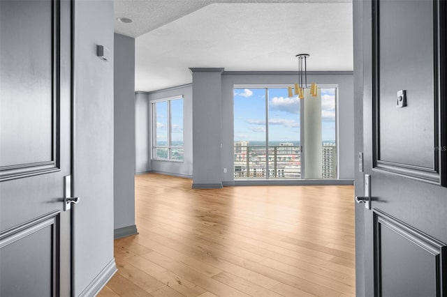 unfurnished room featuring ornamental molding, a textured ceiling, and light hardwood / wood-style floors