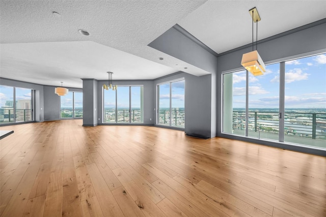 unfurnished living room with ornamental molding, light wood-type flooring, a textured ceiling, and a healthy amount of sunlight