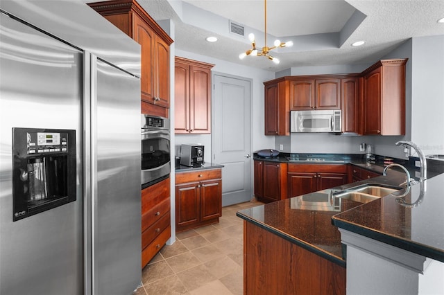 kitchen with stainless steel appliances, hanging light fixtures, a textured ceiling, a chandelier, and a raised ceiling