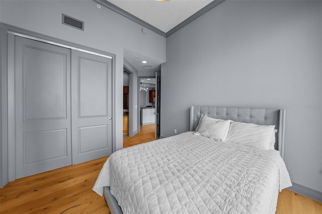 bedroom featuring a closet, light hardwood / wood-style floors, and crown molding