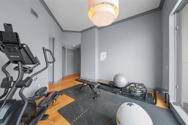 exercise room with light hardwood / wood-style floors and ornamental molding