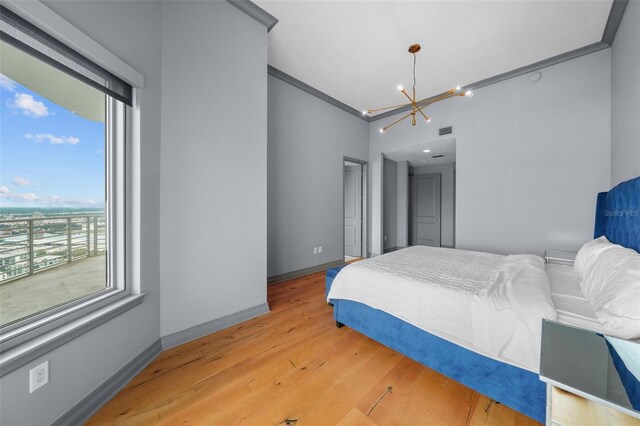 bedroom featuring light wood-type flooring, a notable chandelier, and crown molding