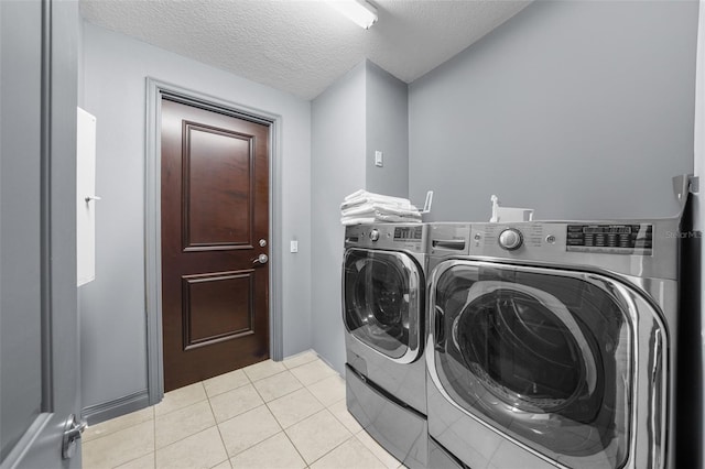 laundry room with washing machine and dryer, a textured ceiling, and light tile patterned flooring