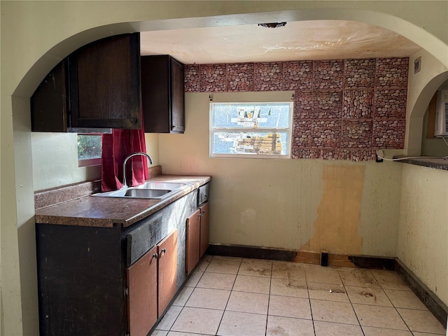 kitchen with dark brown cabinets, sink, and light tile patterned flooring