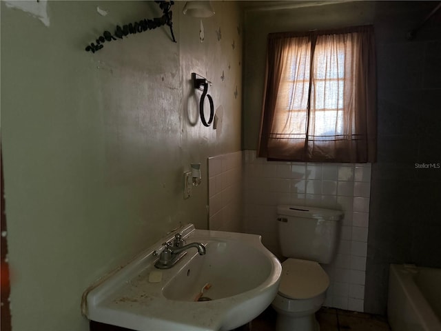 bathroom with sink, toilet, and tile walls