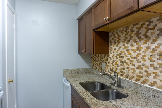 kitchen featuring a sink, white dishwasher, tasteful backsplash, and light stone counters