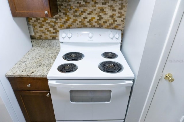 kitchen view of white electric stove, decorative backsplash, and dark brown cabinets