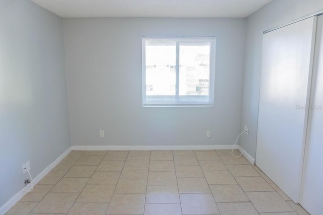 empty room featuring light tile patterned floors and baseboards