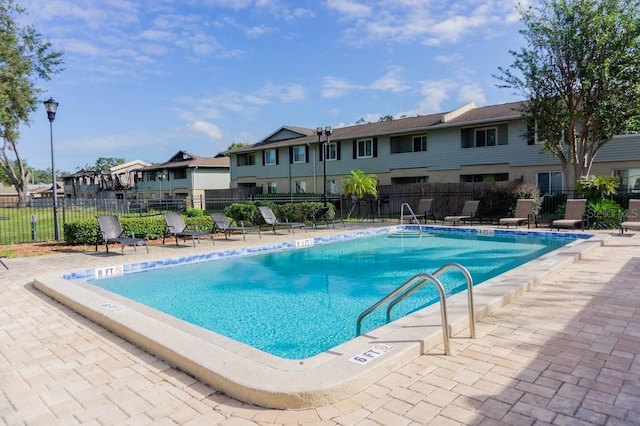 community pool featuring a residential view, a patio area, and fence