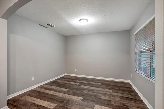 unfurnished room with dark hardwood / wood-style flooring and a textured ceiling