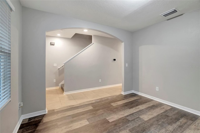 spare room with a textured ceiling and light wood-type flooring