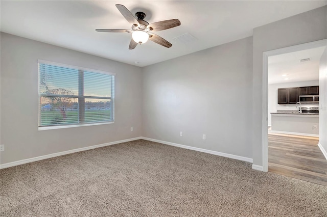 carpeted empty room with sink and ceiling fan