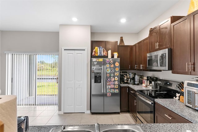 kitchen with dark brown cabinetry, stainless steel appliances, and light tile patterned flooring