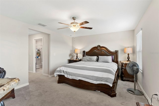 bedroom with connected bathroom, light carpet, and ceiling fan