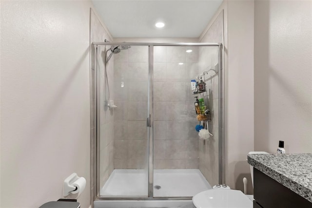 bathroom with toilet, vanity, and a shower with shower door