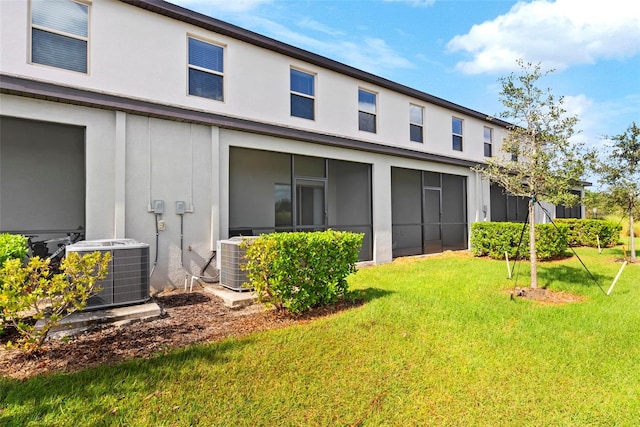 rear view of property with a lawn and central AC