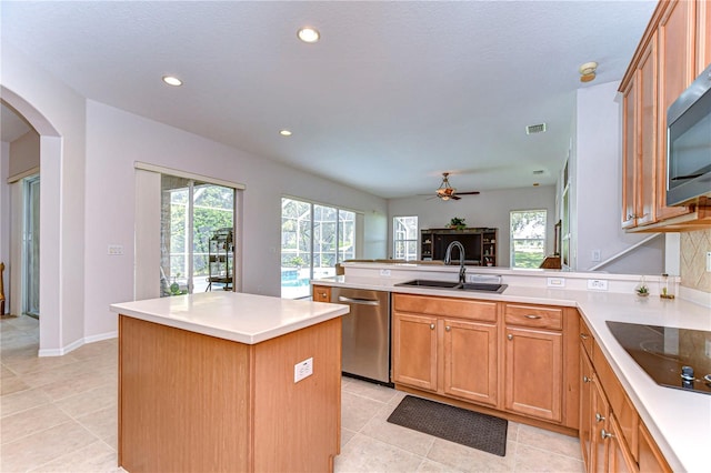 kitchen featuring sink, appliances with stainless steel finishes, ceiling fan, light tile patterned floors, and a center island